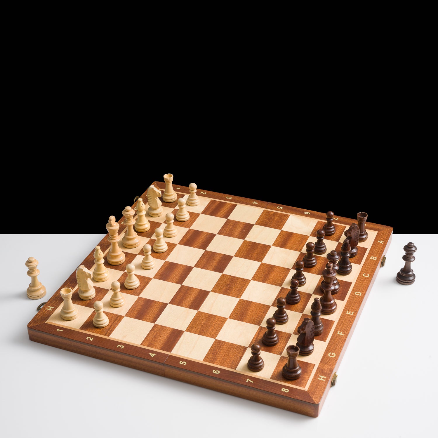 Wooden chessboard with pieces on a white background